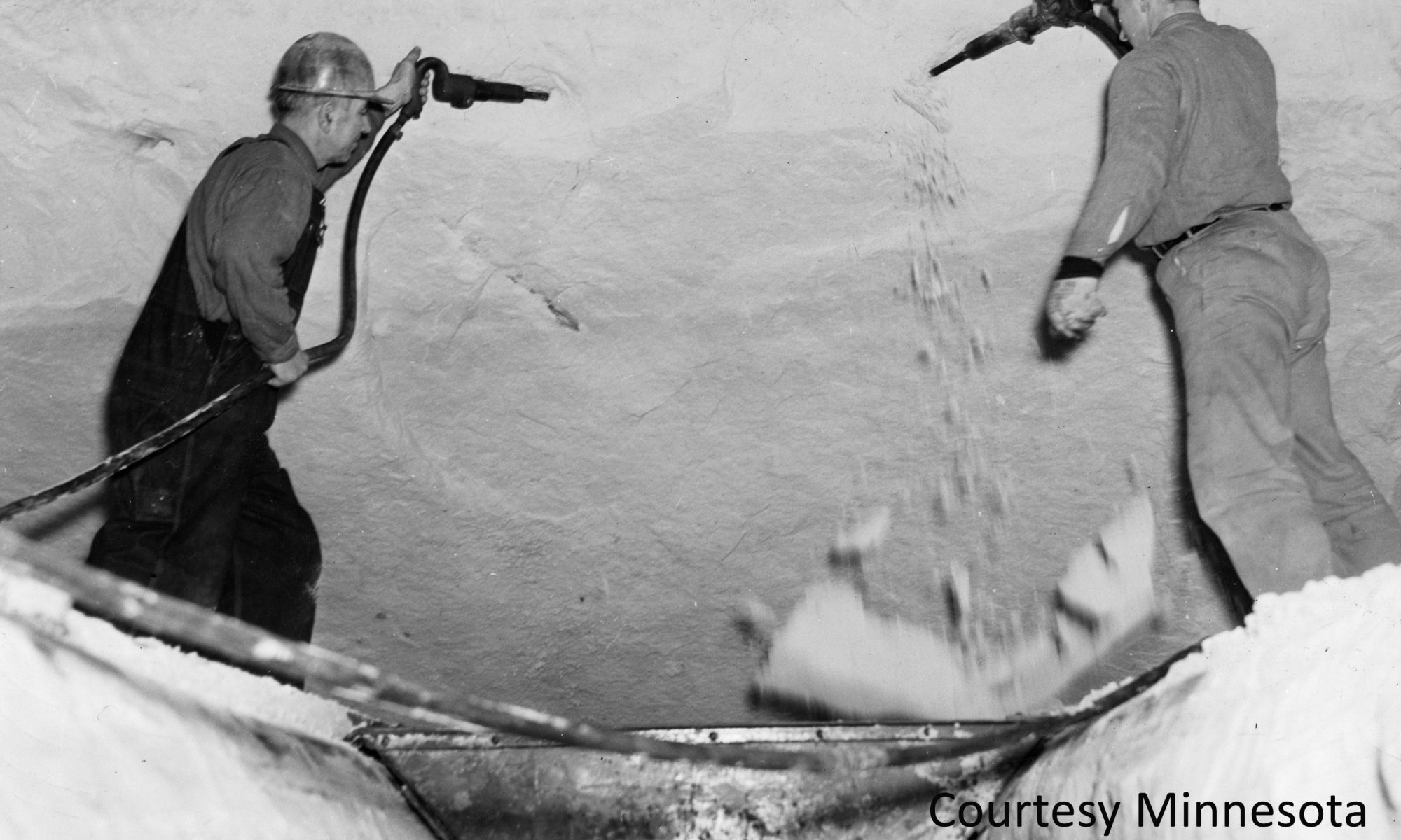 Workers used air guns to blast the silica sand out of the many tunnels that had been excavated 100 feet beneath the Ford plant. The sand was loaded into small electric carts and carried by conveyer up to the furnaces where it would be made into glass. Courtesy Minnesota Historical Society